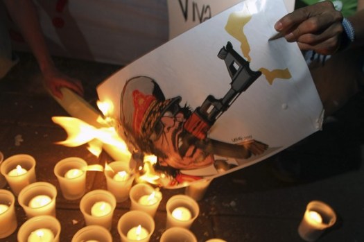 A protester burns a caricature of Libyan leader Muammar Gaddafi during a demonstration in front of the Libyan Embassy in Managua